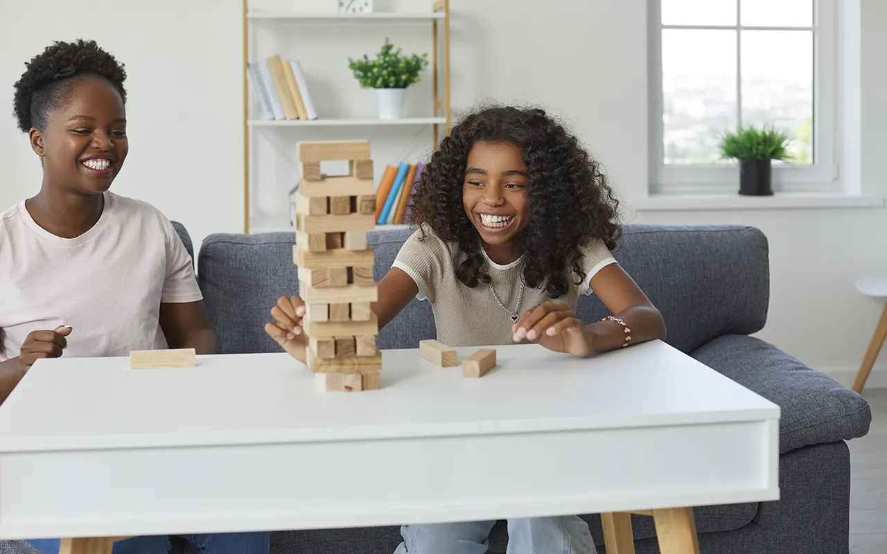Two girls laughing while playing Jenga block tower game