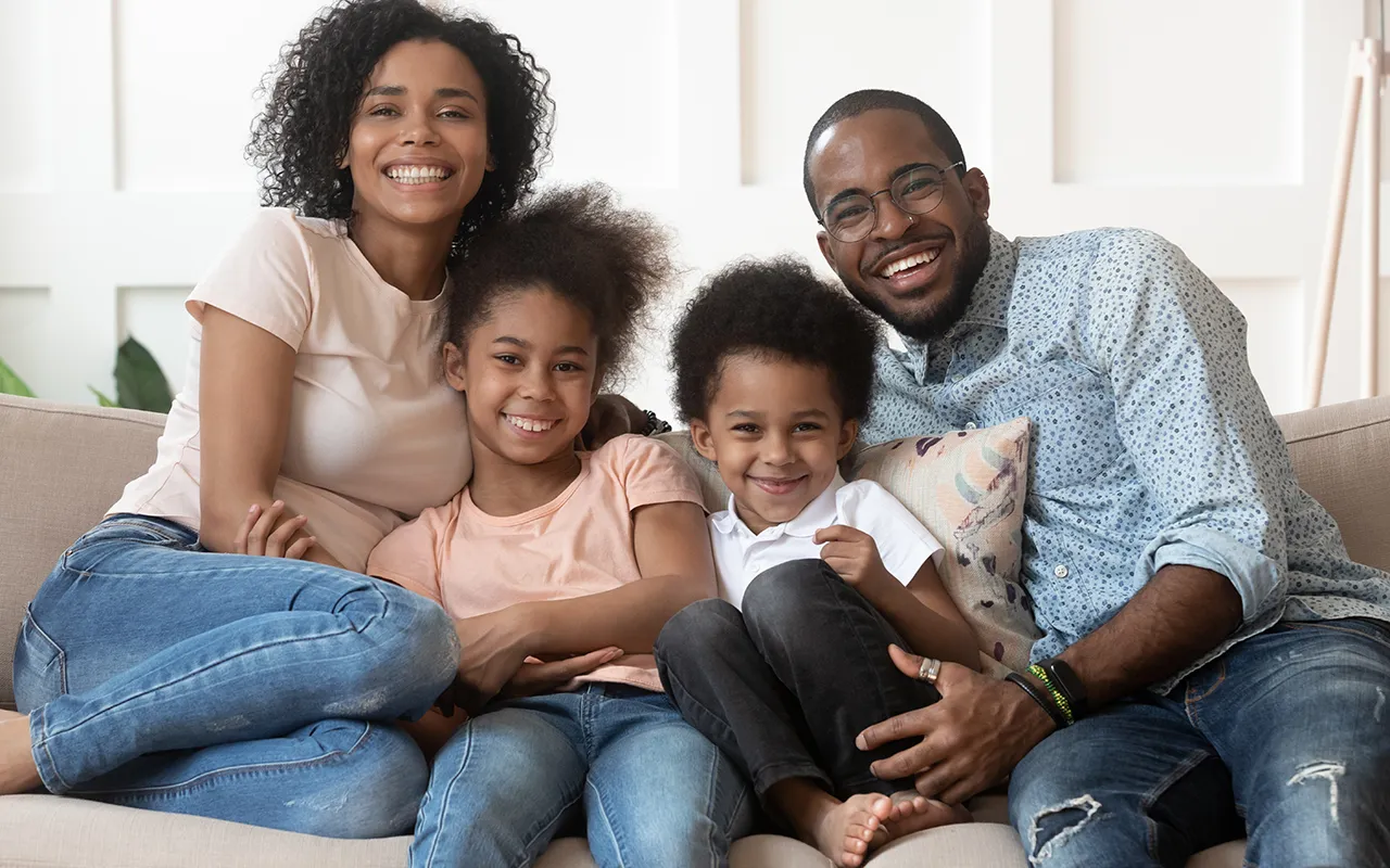 Happy family of four smiling together on a couch