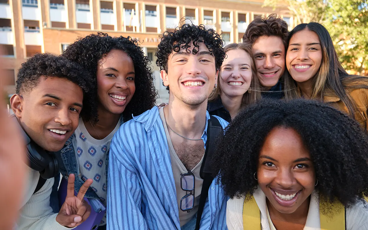 Diverse group of seven smiling college students taking selfie